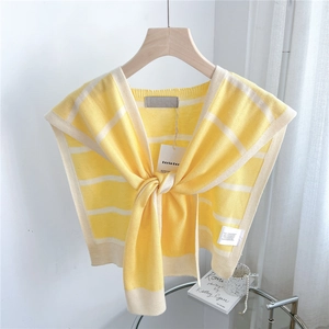 Macro detail of yellow and white striped knit shawl with front tie on wooden hanger