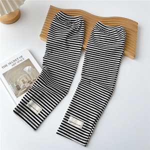 Macro detail of black and white striped ribbed knit arm sleeves with fabric brand tag