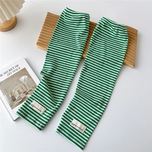 Close-up of green and white striped knit arm sleeves with ribbed texture and white label