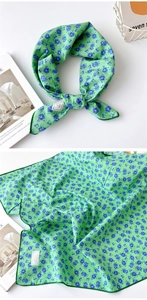 Gros plan d'un foulard carré en coton avec motif floral vert et bords cousus