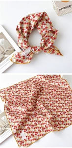 Détail d'un foulard en coton rouge à fleurs avec des bords cousus jaunes