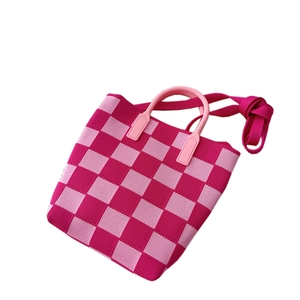 Knitted checkerboard handbag with pink hard handles and a matching shoulder strap