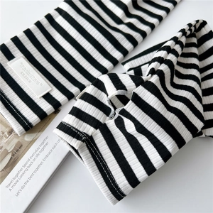 Detail of knitted black and white striped arm sleeves with thumb holes and logo label