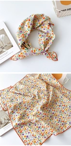 Détail d'un foulard carré en coton avec motif floral orange et bords surjetés
