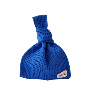 Kleinblaue Strickhandtasche mit Hohlnetzstruktur und gewebtem Markenetikett auf Weiß