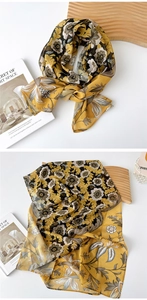 Close-up of vintage floral silk scarf with yellow and black patterns on a satin texture