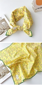 Détail d'un foulard en coton jaune avec imprimé floral lavande et ourlet vert