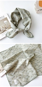 Détail d'un foulard en coton vert sauge doux avec motif floral jaune et bord cousu