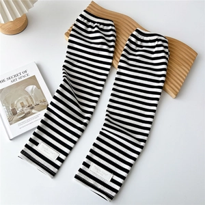 Detail of black and white striped knitted arm sleeves with a square fabric label on the cuff