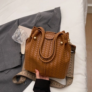Brown woven bucket bag with wide leather straps and vintage bohemian shoulder strap