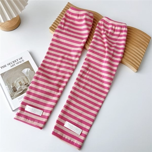 Close-up of pink and white striped knit arm sleeves with brand tag on a desk