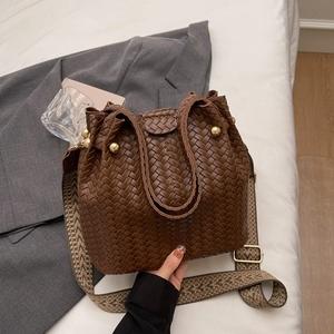 Retro brown woven bucket bag with patterned wide strap shown in a lifestyle setting