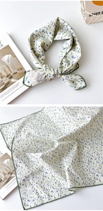 Détail d'un foulard en coton à motif floral bleu et bords cousus en vert doux