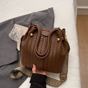 Brown woven bucket bag with gold rivets and vintage colorful geometric shoulder strap