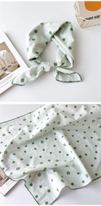Détail d'un foulard en coton vert clair à pois et fleurs avec bordures cousues