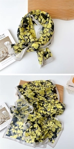 Detail of a thin long chiffon scarf featuring yellow and black floral prints on white surface