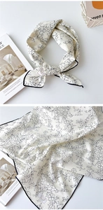 Détail du foulard en coton à motif floral montrant la texture tissée et l'ourlet noir