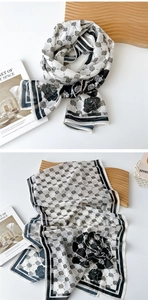 Detail of a thin silk scarf featuring black roses, grey floral prints, and striped borders