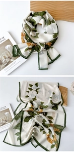 Detail of floral chiffon scarf featuring white roses, gold chains and dark green edges