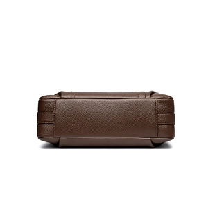 Bottom view of deep brown leather crossbody bag featuring pebbled texture and stitching
