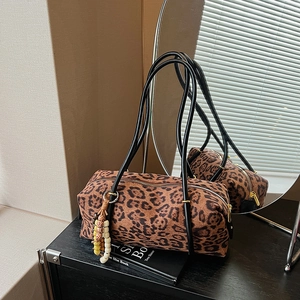 Vintage leopard print boston bag with black handles and beaded charm on dark surface