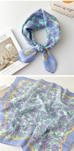 Detail eines hellblauen quadratischen Schals mit lila Gänseblümchen und gelbem Wellenrand