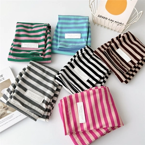 Striped knit arm sleeves in various colors with a minimalist brand label on white background