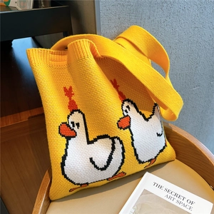 Close-up of a yellow knitted tote bag featuring cute cartoon white duck patterns