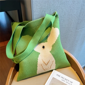 Close-up of green knitted tote bag with cute white bunny pattern and thick woven texture