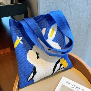 Macro detail of knit blue tote bag featuring white rabbit and flower jacquard pattern