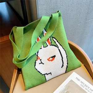 Cute green knitted tote bag with white cartoon rabbit jacquard on a wooden chair