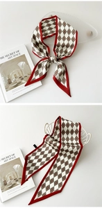 Détail d'un foulard en soie à losanges rouge et blanc noué sur un panier blanc épuré