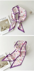 Détail d'un foulard en soie à fleurs avec bordure violette décorant un panier élégant