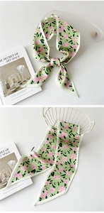 Détail d'un foulard étroit en soie à motif floral avec passepoil blanc sur panier
