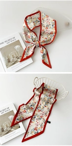 Détail d'un foulard étroit en soie à motif marguerites avec une bordure rouge vif