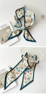 Gros plan détaillé d'un foulard étroit en satin fleuri avec des bordures bleu canard foncé