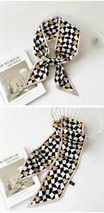 Détail d'un foulard en soie à damier avec coeurs jaunes noué sur un plateau blanc