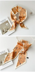 Détail d'un foulard étroit en soie orange avec motifs floraux blancs dessinés à la main