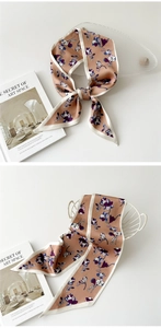 Détail d'un foulard twilly floral rose poudré noué en ruban sur un panier blanc