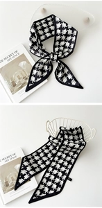 Gros plan sur un foulard en soie à carreaux noir et blanc noué sur un sac élégant