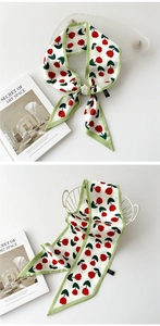 Détail d'un long foulard twilly en soie avec motif tulipe rouge et bordure verte