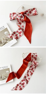 Détail d'un foulard en soie à fleurs rouges avec motif à carreaux rose et pointes fines