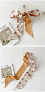 Détail d'un foulard en soie avec motif géométrique et revers orange pour cou ou cheveux