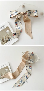 Détail d'un foulard en soie champagne avec imprimés fleurs et nœud stylisé
