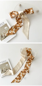 Détail d'un ruban en mousseline avec motif floral blanc sur tissu jaune brun soyeux