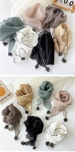 Detail of lightweight cotton linen scarf showing wavy edges and pom-pom trim accents
