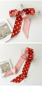 Détail d'un ruban à cheveux à fleurs rouge et rose avec texte cursif élégant