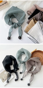 Detail of soft cotton linen triangle scarf featuring decorative mini ball fringe edges