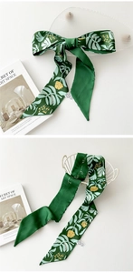 Détail d'un foulard en soie vert émeraude avec imprimés tropicaux et étiquette