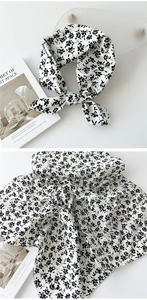 Détail d'un foulard en lin et coton doux avec fleurs noires sur tissu blanc pur